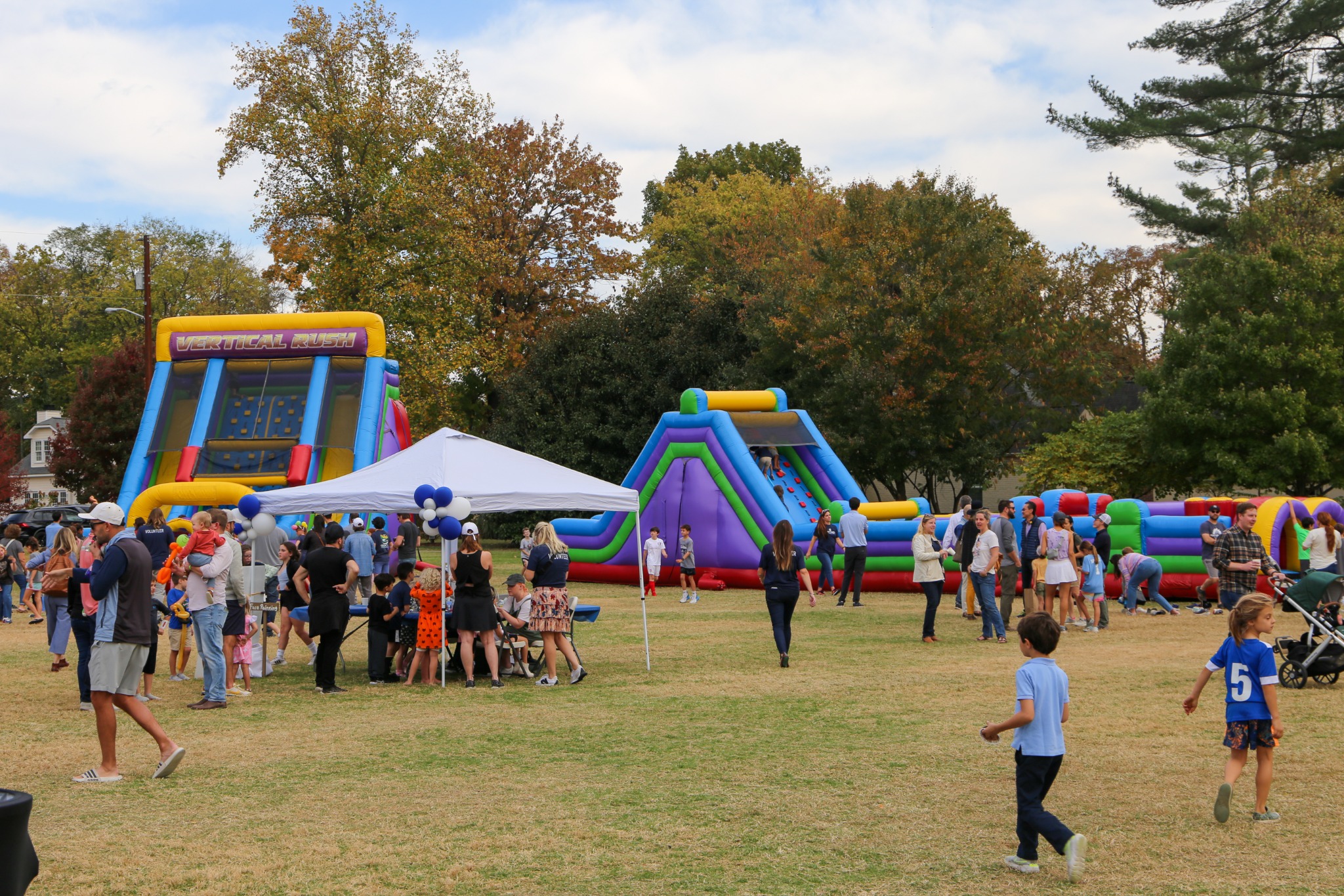 Families and children gathering at a Harding Fall Fest with colorful inflatable slides